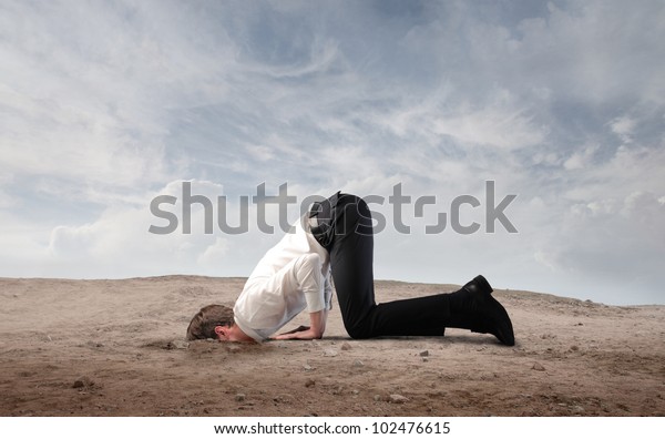 Joven hombre de negocios enterrando su cabeza en la arena