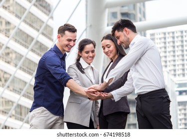 young businessman and businesswoman express teamwork, stacking hands at outdoor office
