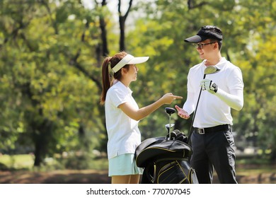 Young Businessman And Caddy Playing Golf In The Lawn In The City Center. Planning And Looking For Success. Use For Background And Design. 