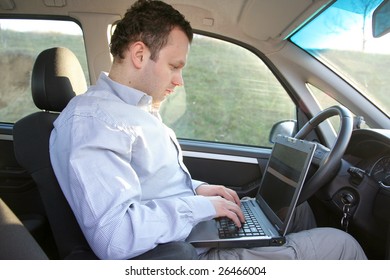 Young businessman in the car working on notebook during driving