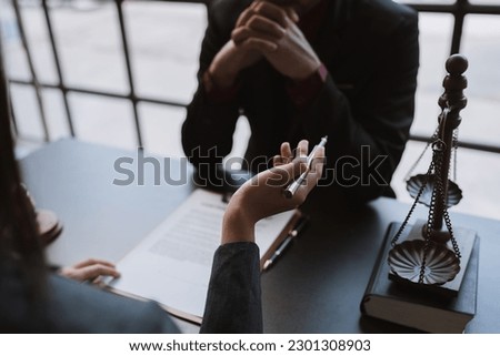 Young businessman concentrating on signing a contract with a skilled female lawyer and financial adviser explaining in detail legal information for signing a contract at a meeting in an office.