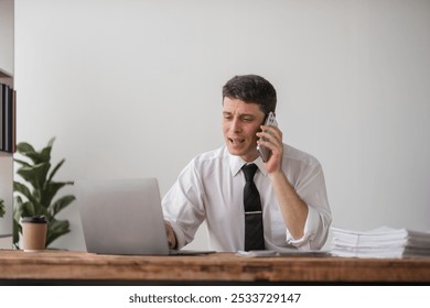 Young Businessman Disappointed at Work, Stressful Office Environment, Frustrated Professional on Phone Call, Overwhelmed with Tasks, Corporate Stress, Workplace Challenges, Business Struggles - Powered by Shutterstock