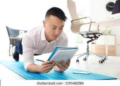 Young businessman doing exercises in office. Workplace fitness - Powered by Shutterstock