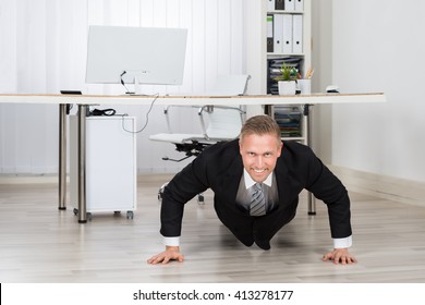 Young Businessman Doing Pushup At Work In Office