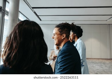 Young businessman with dreadlocks smiling while engaging with colleagues in a professional and happy work environment. - Powered by Shutterstock