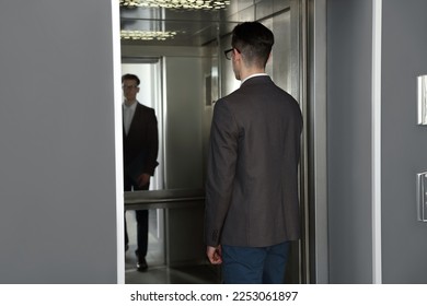 Young businessman entering modern elevator, back view - Powered by Shutterstock