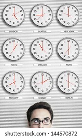 Young businessman in front of clocks showing time across the world