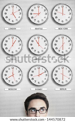 Young businessman in front of clocks showing time across the world