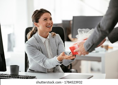 Young businessman giving his colleague present in office. Young man surprise beautiful businesswoman in office. - Powered by Shutterstock