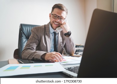 Young businessman in glasses talking to phone in his personal office. - Powered by Shutterstock