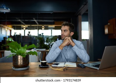 Young Businessman Going Over Notes And Working On A Laptop At His Desk In A Quiet Office