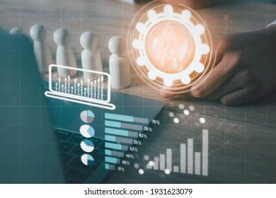 A Young Businessman Grabs A Light Bulb, A Laptop Computer, A Wooden Puppet, A Growth Graph On His Desk, Concept. Business Growth And Planning With Modern Technology, Data Collection And Analysis.