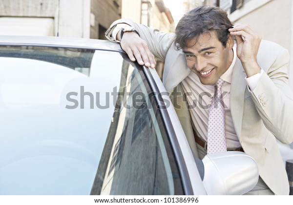Young businessman grooming himself in the mirror of\
a parked car in the city.
