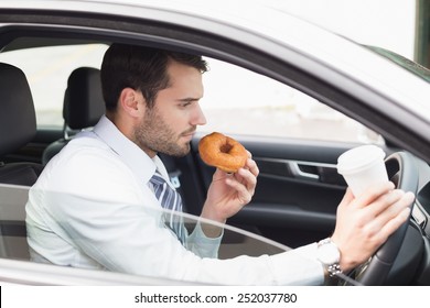 Young Businessman Having Coffee And Doughnut In His Car