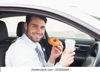 Young Businessman Having Coffee And Doughnut In His Car