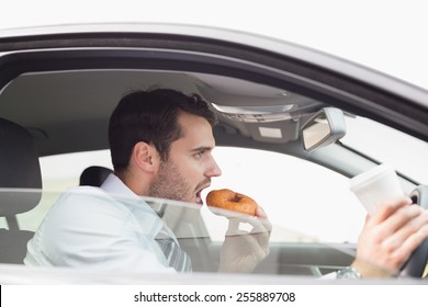 Young Businessman Having Coffee And Doughnut In His Car