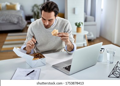 Young Businessman Having Lunch Break While Working On Laptop At Home. 