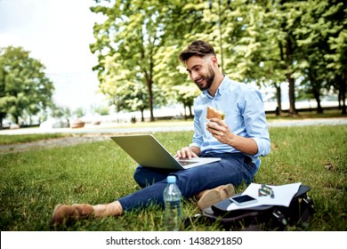 Young businessman having sandwich for lunch in the park and working on laptop - Powered by Shutterstock