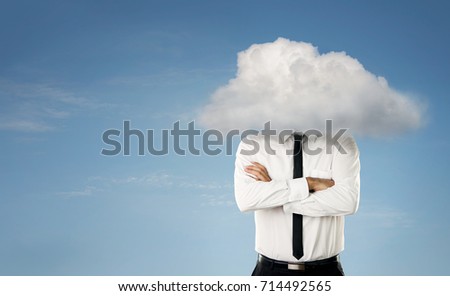 Young businessman with head in the clouds over blue sky background with copy space
