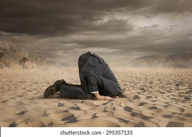 Young businessman hiding head in the sand - Shutterstock ID 295357133