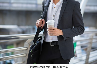Junge Geschäftsleute, die eine Tasse Kaffee bei einem Spaziergang in der Stadt halten. Geschäftsmann