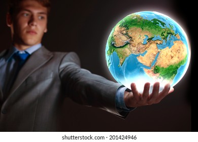 Young businessman holding Earth planet in hand. Elements of this image are furnished by NASA