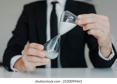 Young businessman holding hourglass. Concept of time management and deadline. - Powered by Shutterstock