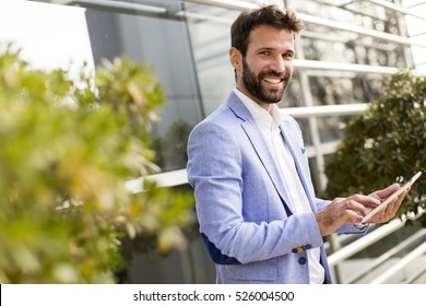 Young businessman holding tablet in hands outdoor