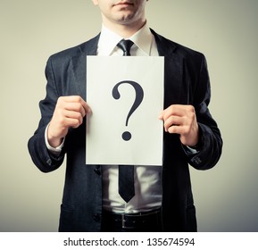 Young businessman holding a white billboard with a question mark on it - Powered by Shutterstock