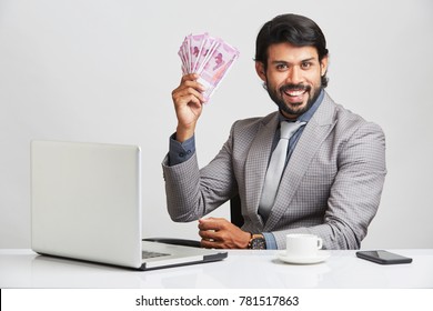 Young Businessman With Indian Money On Desk.