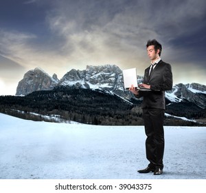 young businessman with laptop on a mountains landscape background