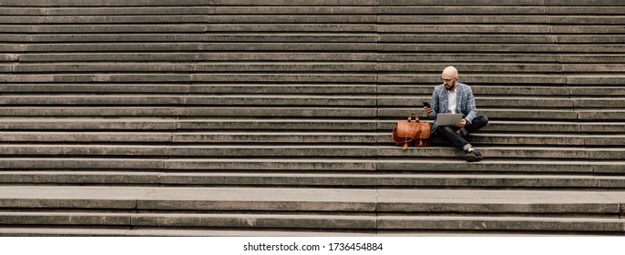  young businessman with laptop sitting on stairs ramp
