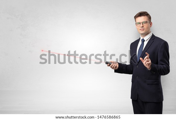 Young businessman with laser pointer and copyspace\
white wall