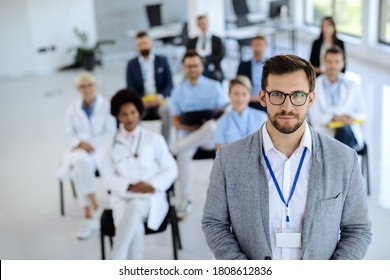 Young businessman leading a seminar to group of healthcare workers and business people in board room and looking at camera. 