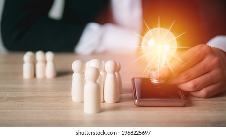 A young businessman with a light bulb in his hand, Mobile phones, wooden dolls, all on your desk, New technologies, big data, and business process strategies, innovative solutions.