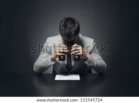 Young businessman looking to a document through a binoculars