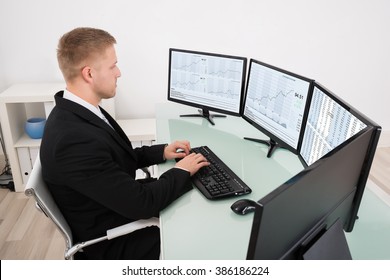 Young Businessman Looking At Graph On Multiple Computer Screen