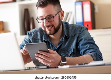 Young businessman looking at tablet in his office - Shutterstock ID 290601458