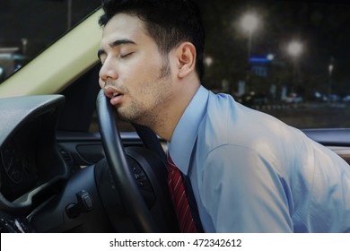 Young Businessman Looks Tired And Sleeping Inside A Car On The Steering Wheel