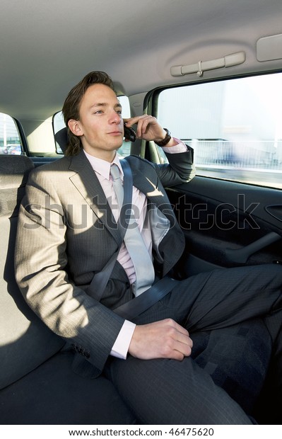 A young businessman making a call in the backseat of\
a taxi