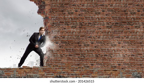 Young businessman making effort to move brick wall - Powered by Shutterstock