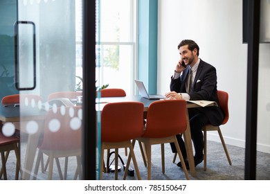 Young businessman making a phone call in a boardroom