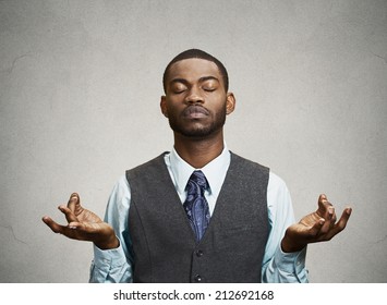 Young Businessman Meditating, Eyes Closed, Isolated Grey Wall Background. Stress Relief Techniques At Work Concept. Take A Deep Breath.