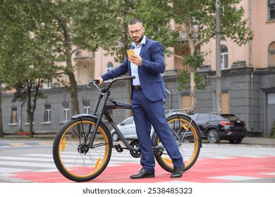 Young businessman with mobile phone and bicycle crossing road on city street - Powered by Shutterstock