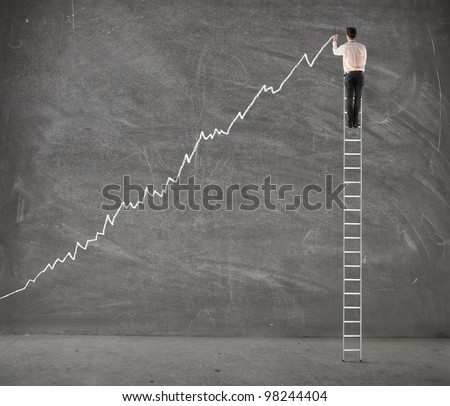 Young businessman on a ladder charting a positive trend graph