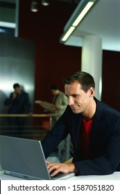 Young Businessman On Laptop In Office Setting