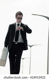 A Young Businessman (or Spy) Dressed Up And Walking With A Metallic Briefcase.