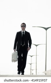 A Young Businessman (or Spy) Dressed Up And Walking With A Metallic Briefcase.