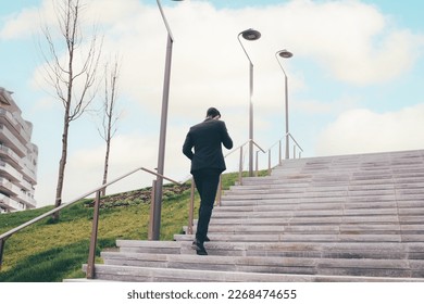 Young businessman outdoors walking stairs talking smartphone, ambition for future - Powered by Shutterstock