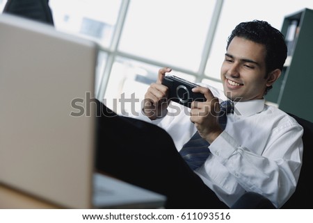 Young businessman playing with Playstation Portable